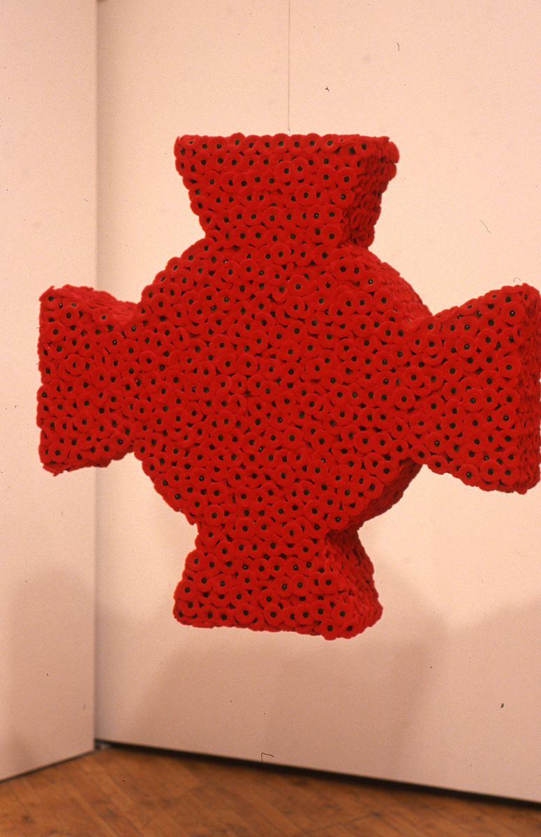 Installation view of the group show trophy, sculpture of a red knit cross.