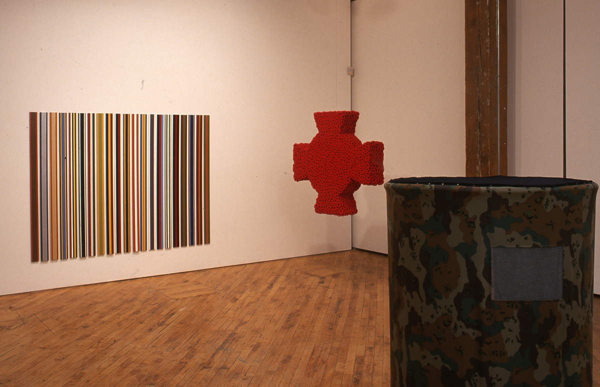Installation view of the group show trophy., image of many vertical lines, and a Red knit Cross.