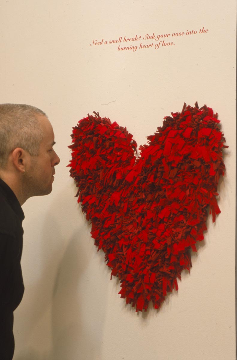 Clara Ursitti: Installation View, man looking at heart sculpture.