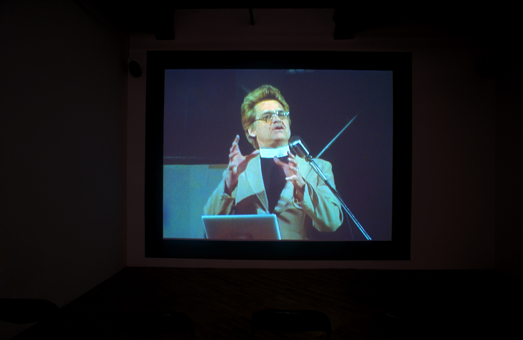 Nancy Nicol: Projection of a man speaking to an audience.