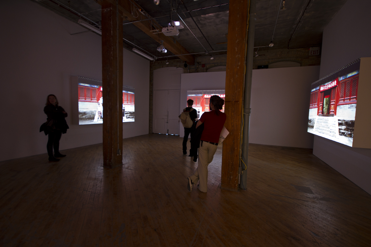 Installation view, projections of Chinese architecture, with image of person in the foreground.