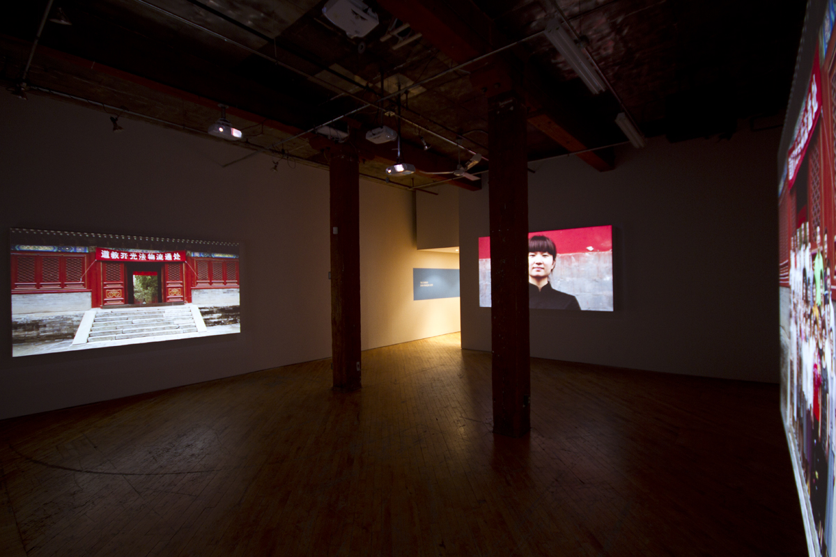 Installation view, projections of Chinese architecture, with image of person in the foreground.