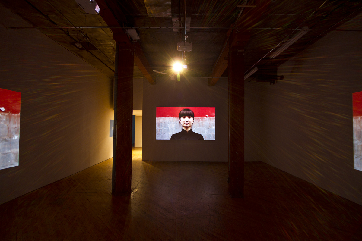 Installation view, projections of Chinese architecture, with image of person in the foreground.