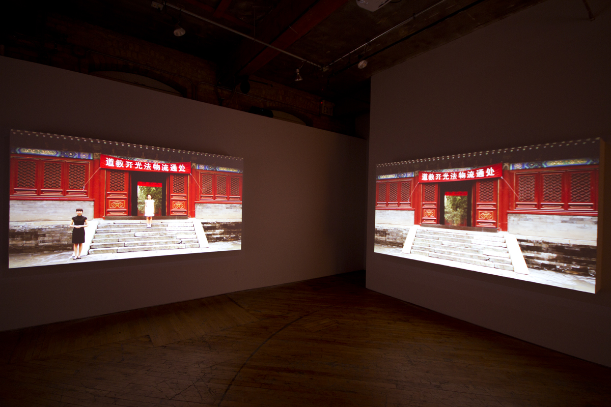 Installation view, projections of Chinese architecture, with image of person in the foreground.