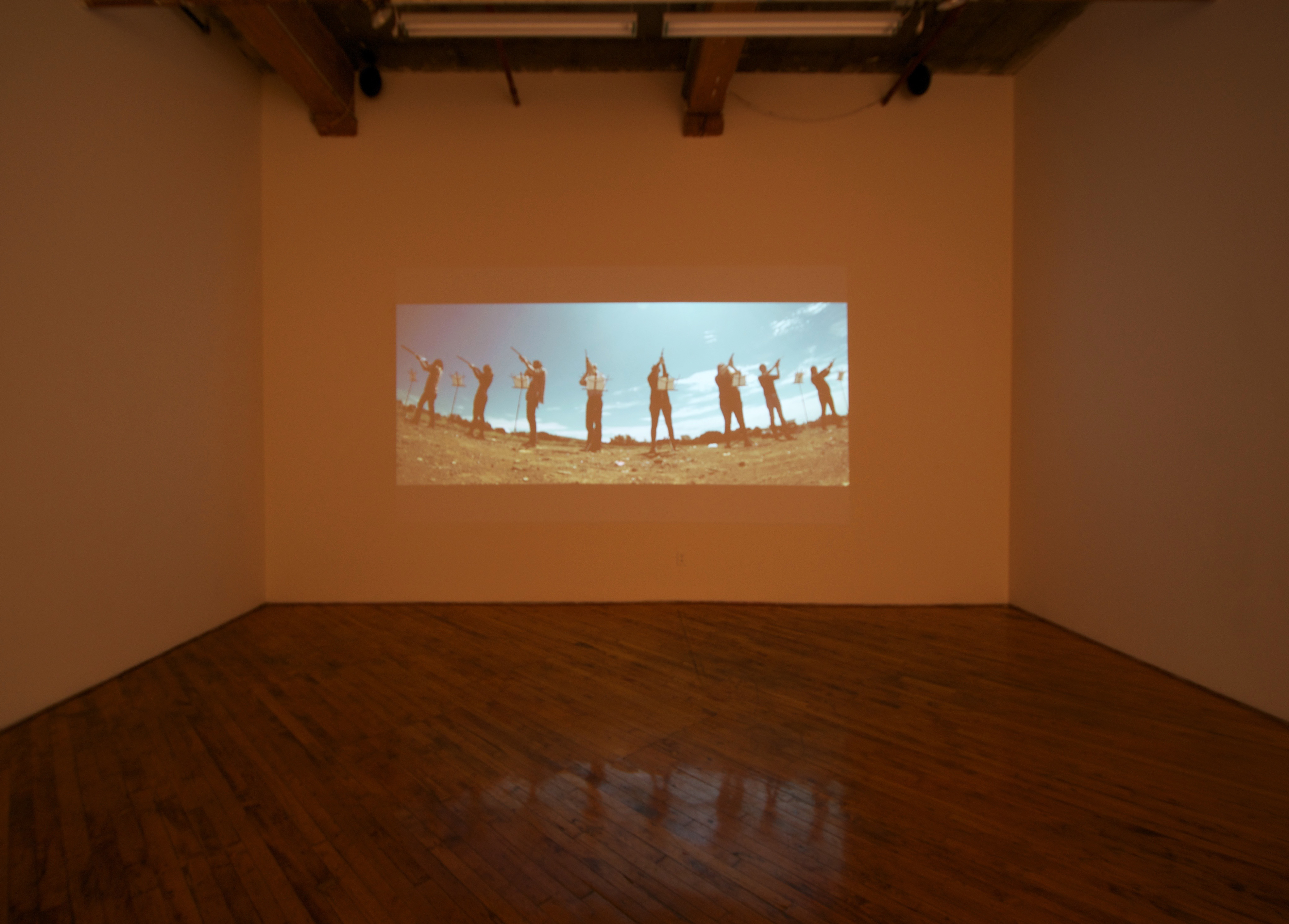 Raven Chacon, installation view, video projection, of people firing guns.