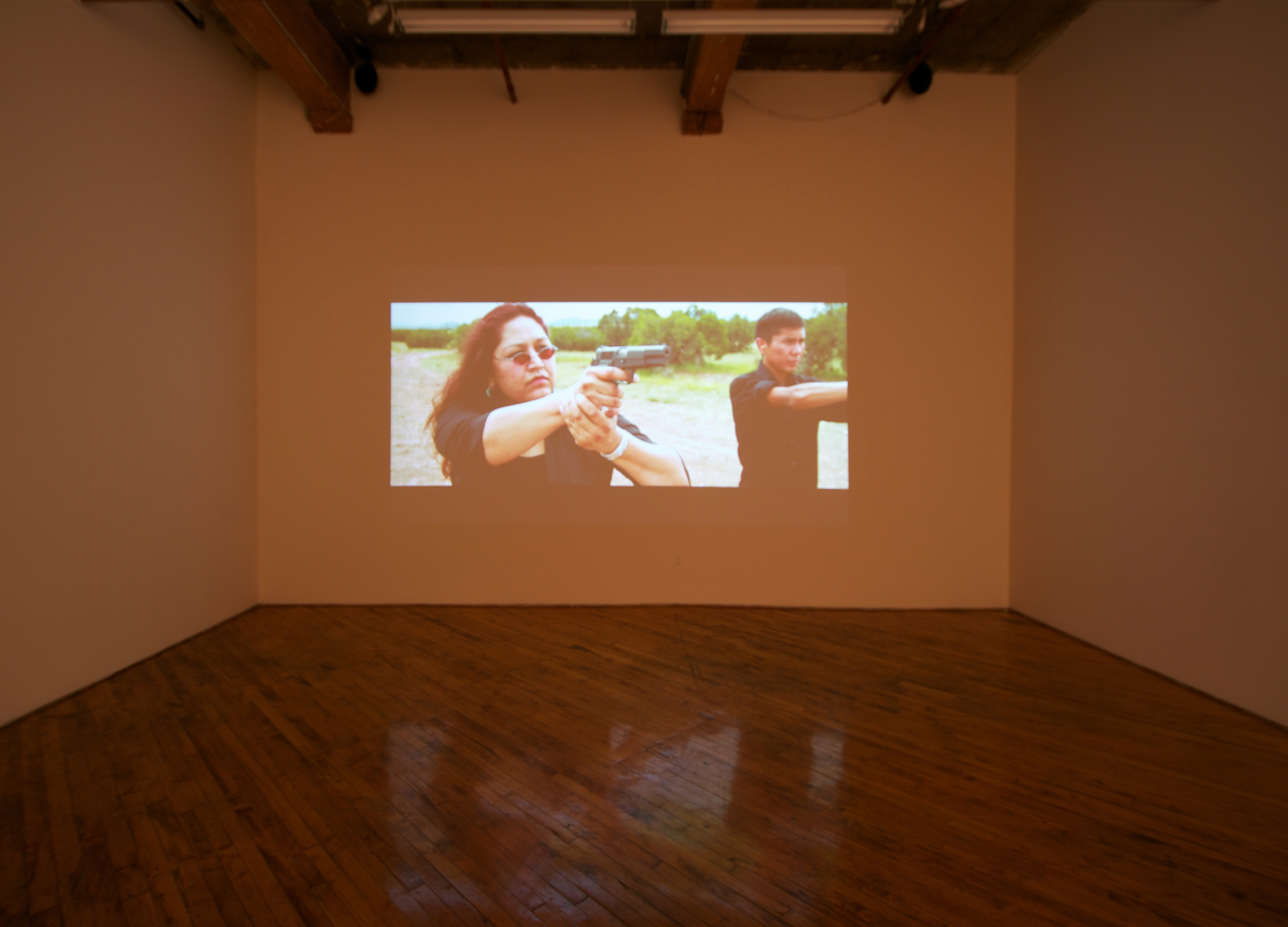 Raven Chacon, installation view, video projection, of people firing guns.