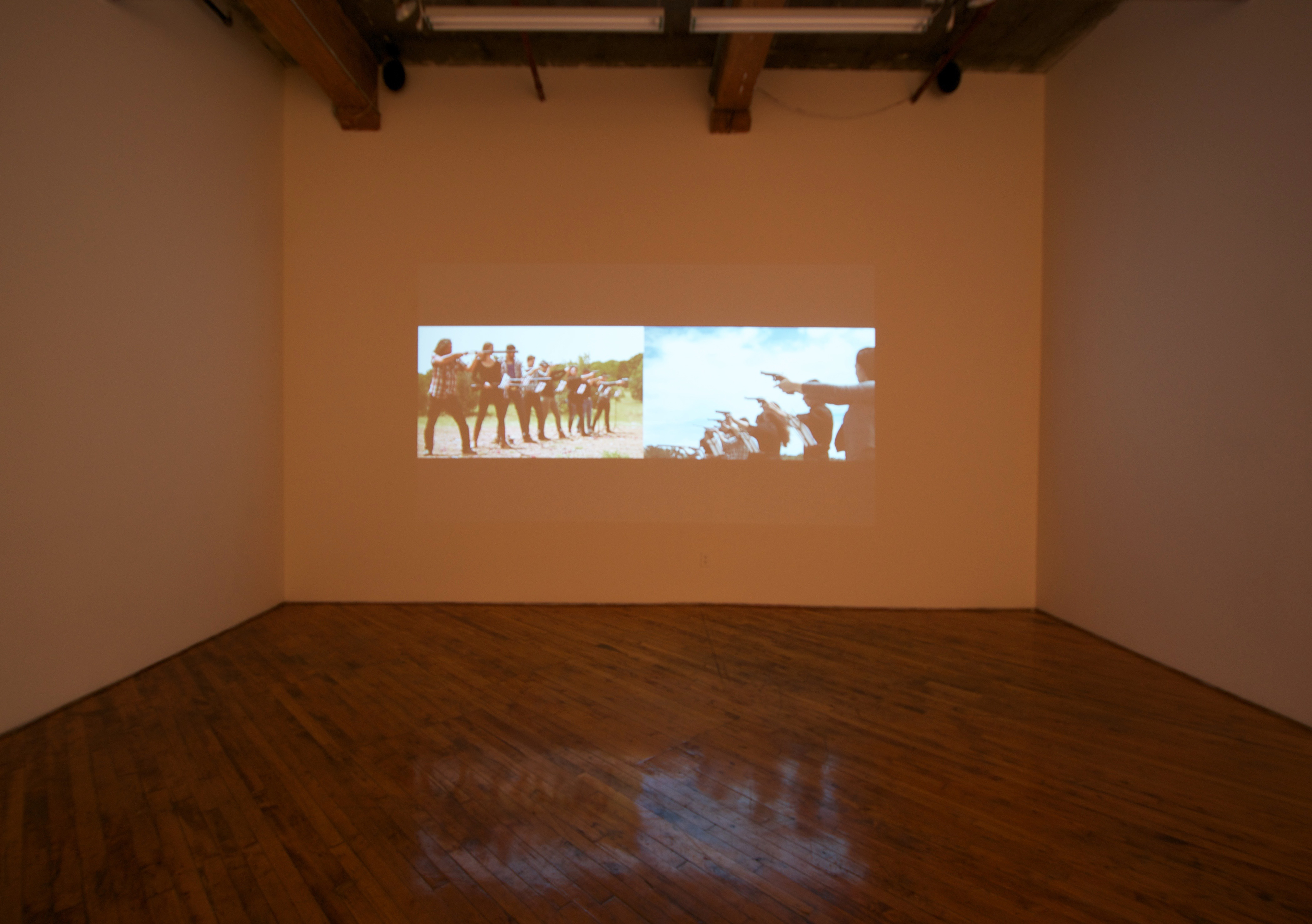 Raven Chacon, installation view, video projection, of people firing guns.