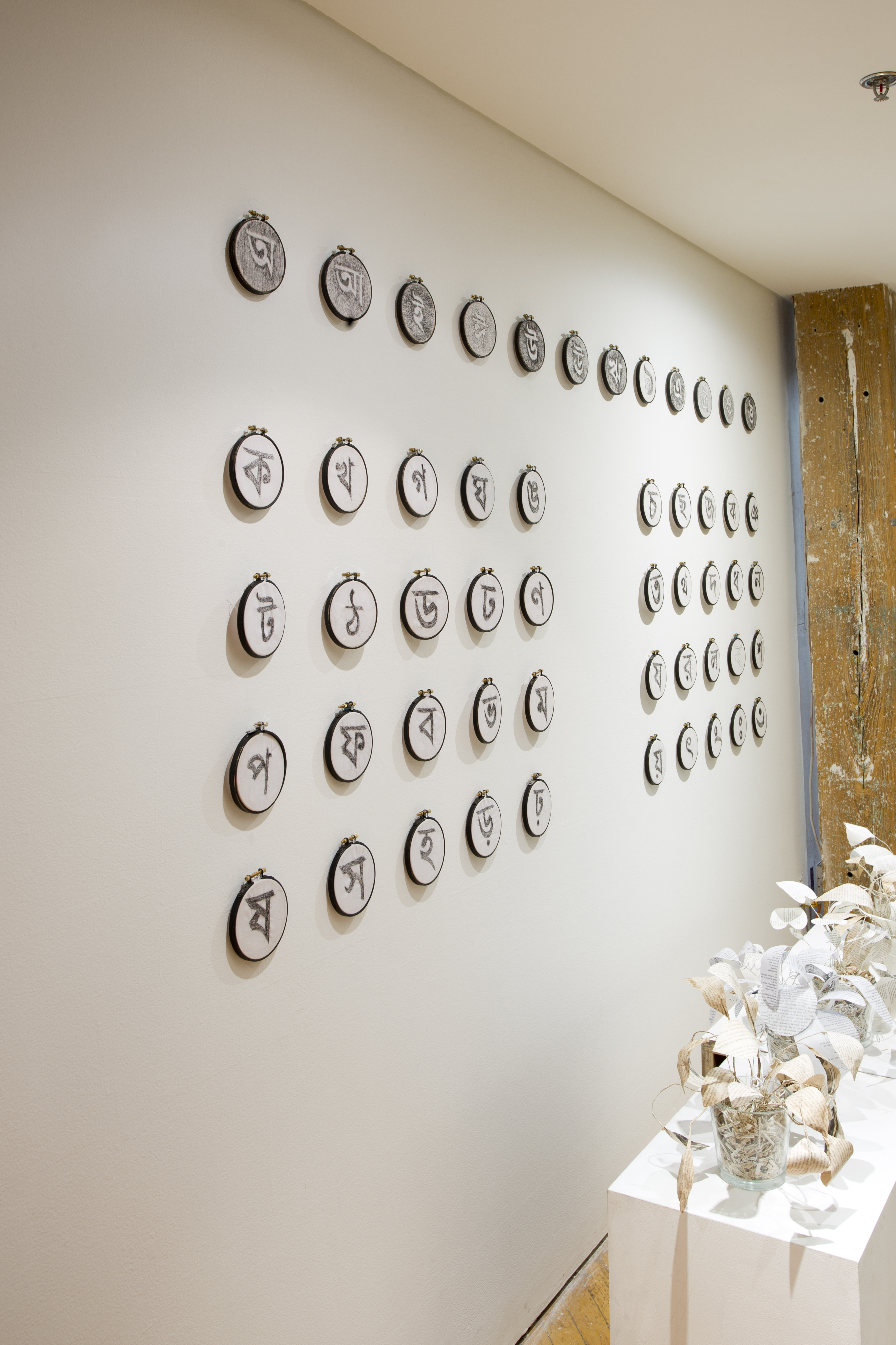 Asma Sultana, window installation, calligraphy symbols, created using hair crochet on mini circular canvases, displayed in rows.