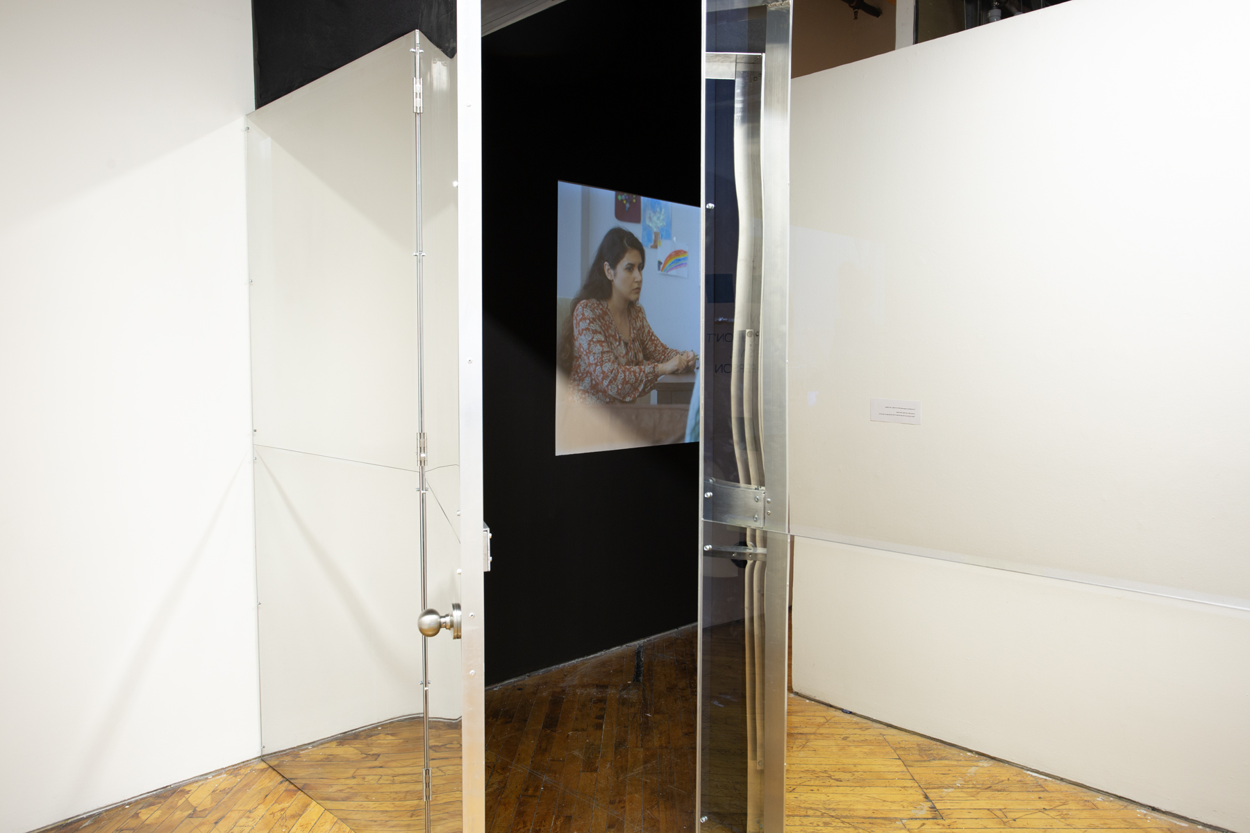 Zinnia Naqvi, view of installation, reflective door opening and and projection.