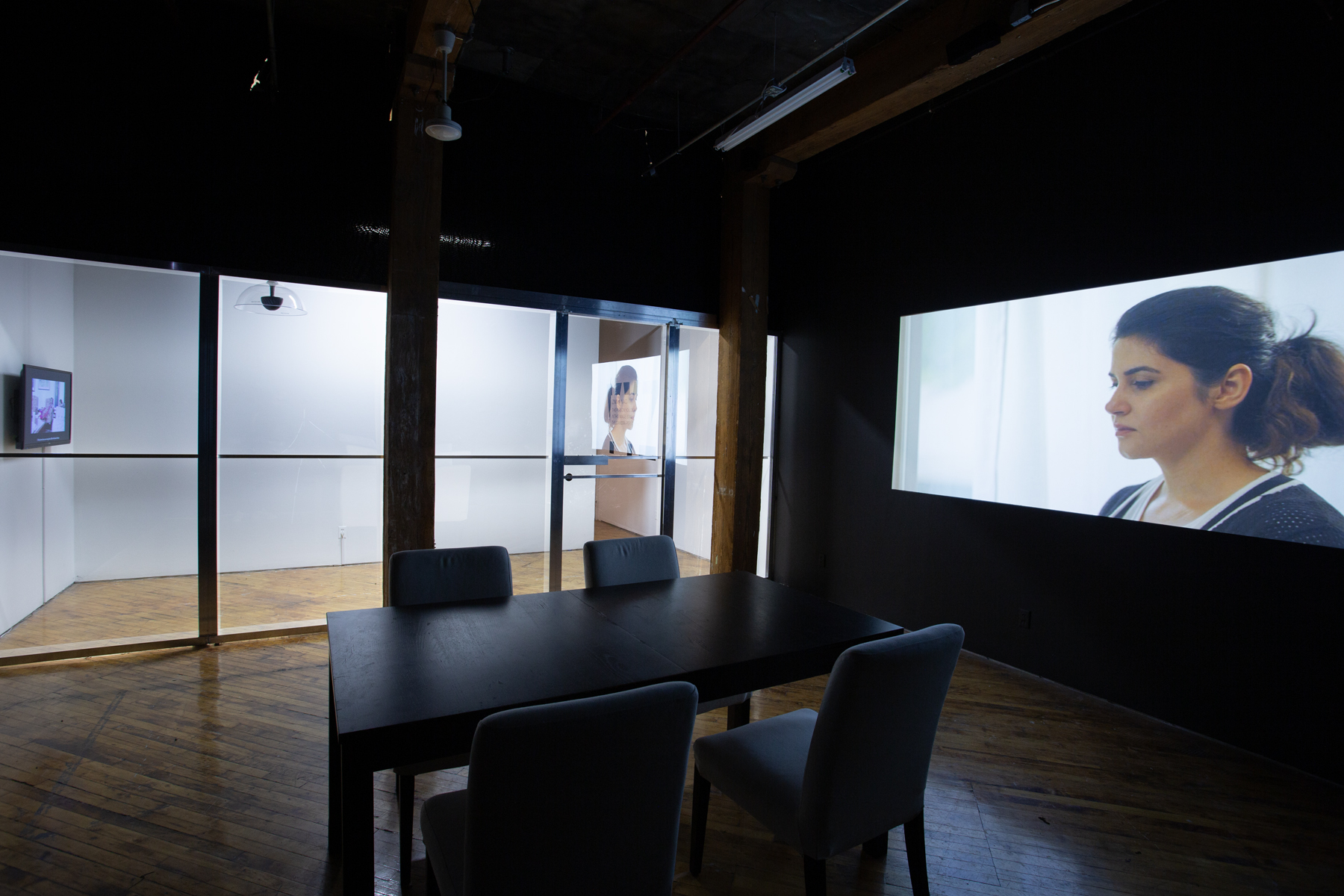 Zinnia Naqvi, view of installation, view of projection and table with chairs.