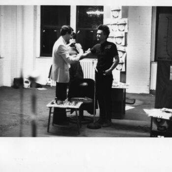 Old black and white photograph of three artists interacting in a studio