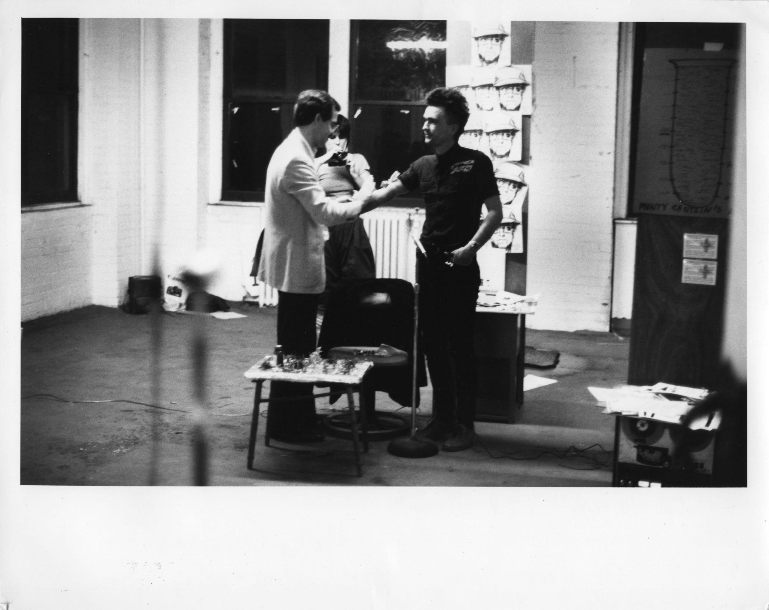 Old black and white photograph of three artists interacting in a studio