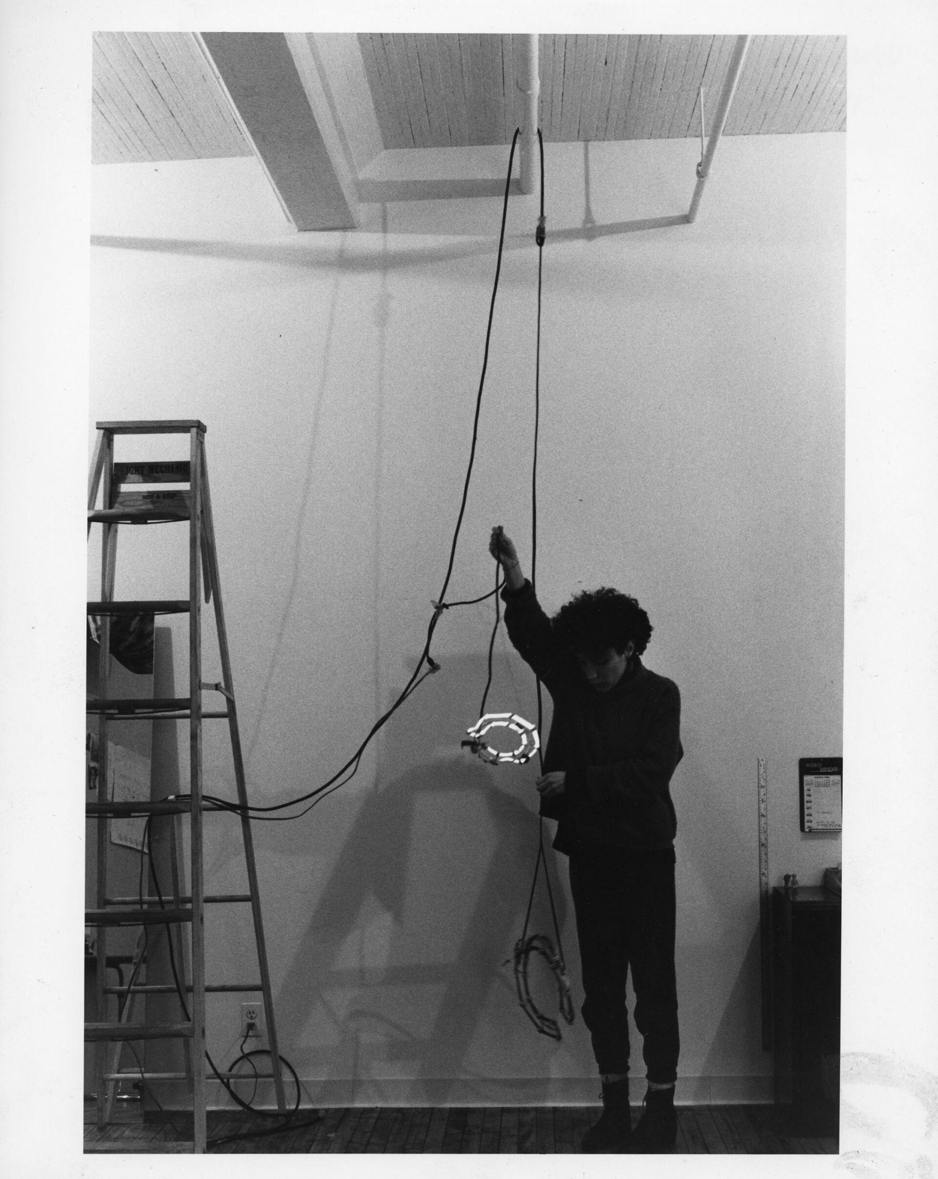 Black and white photo of an artist installing art