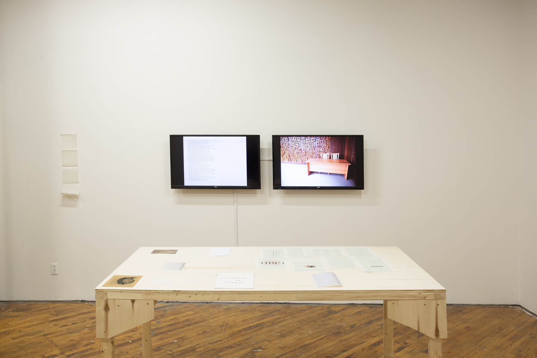 Yusuf Hassan, installation view, two monitors and a table in the foreground.