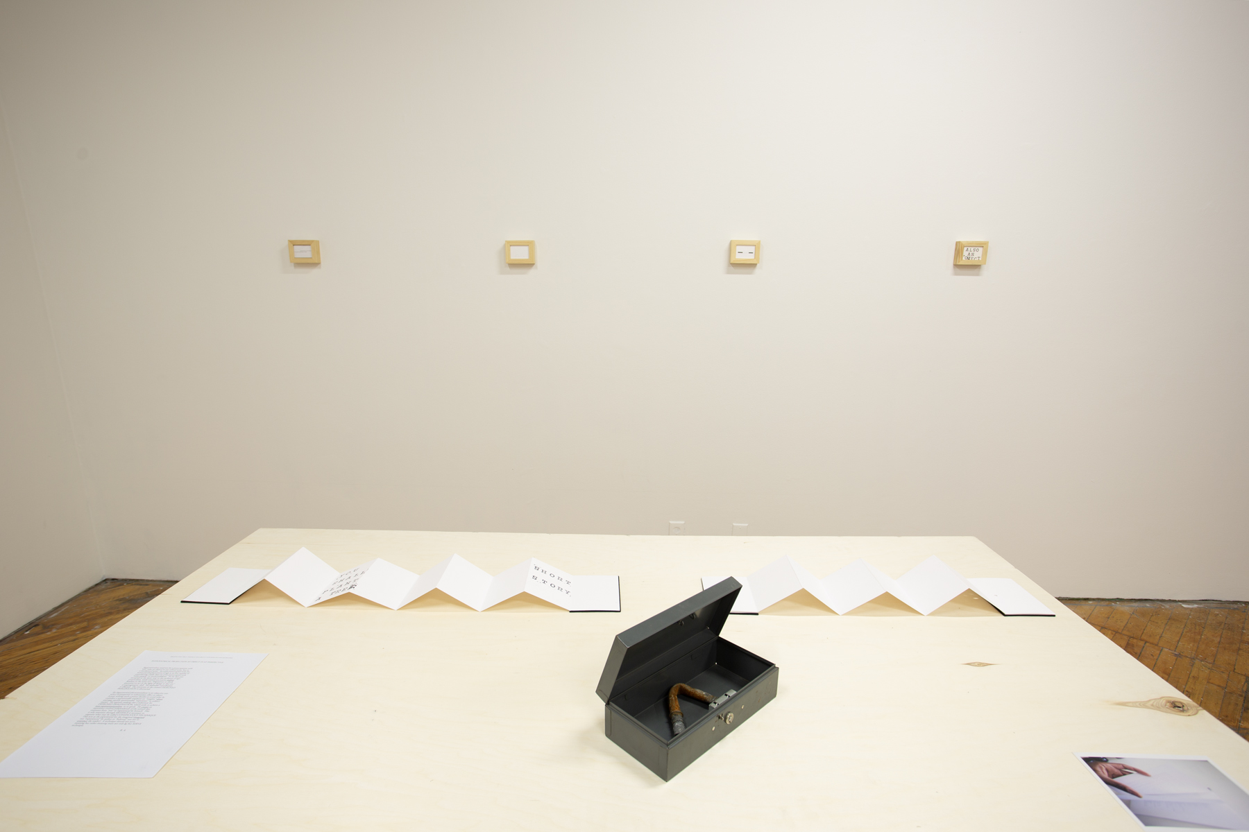 Yusuf Hassan, installation view, table with art displayed.