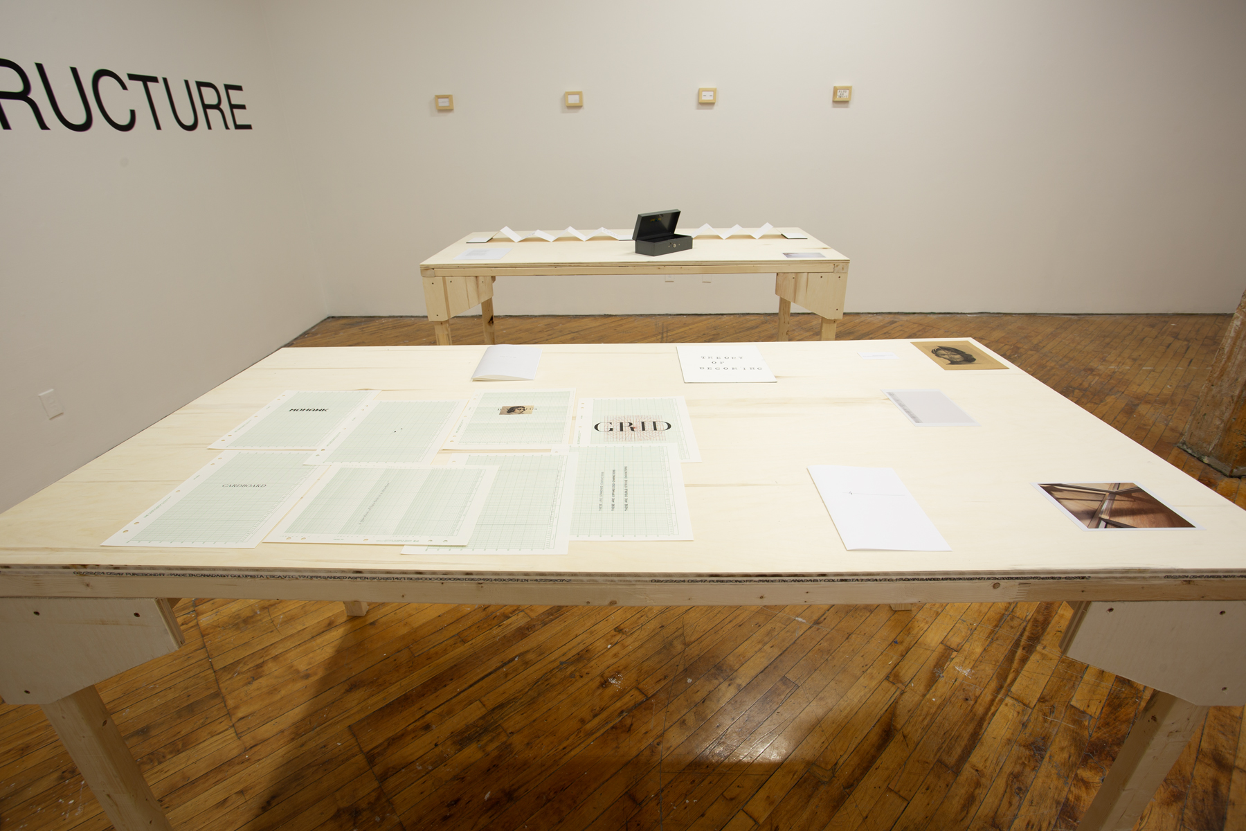 Yusuf Hassan, installation view, two tables with art displayed.