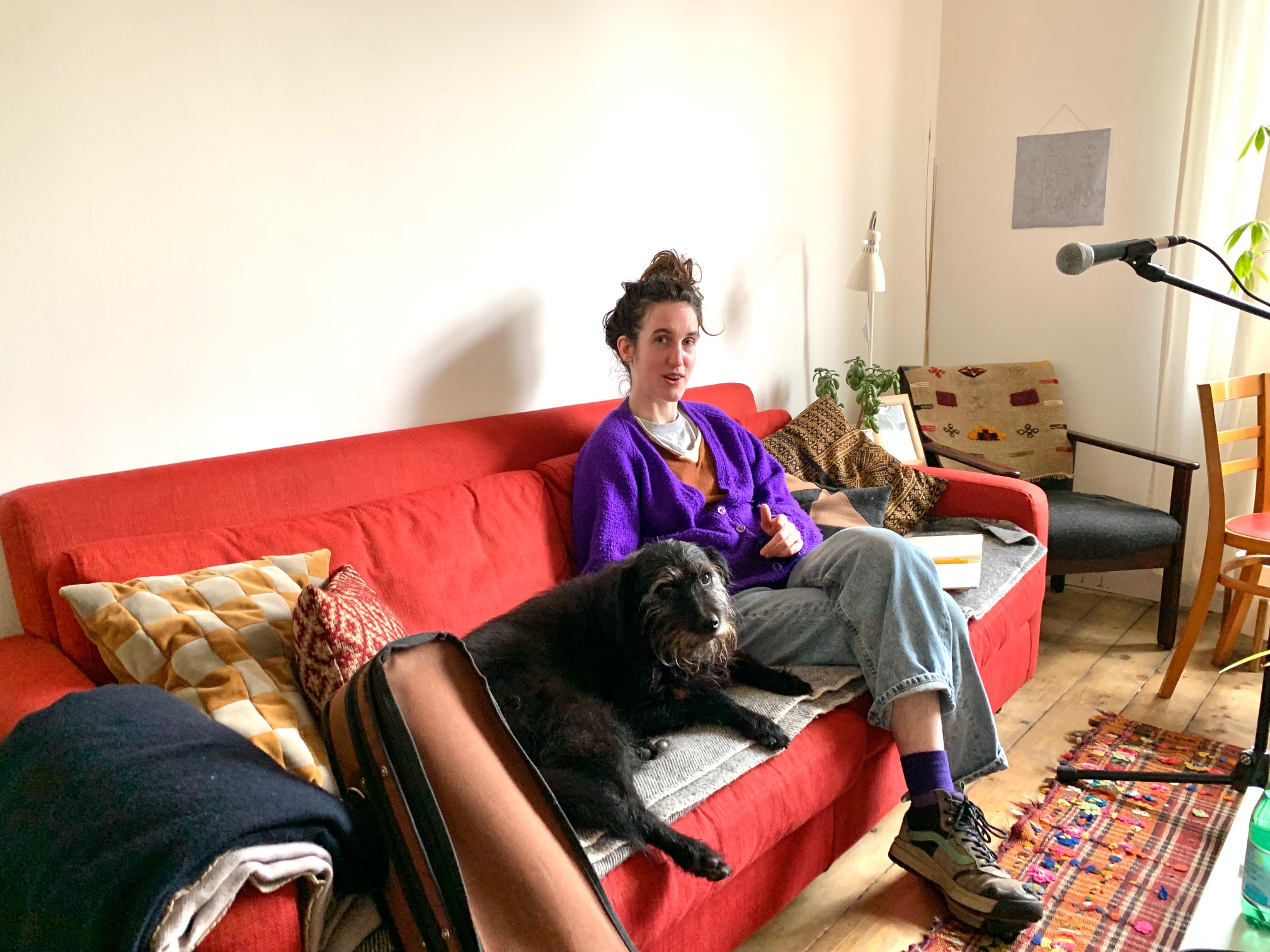 A photo of a person and dog sitting on a red couch