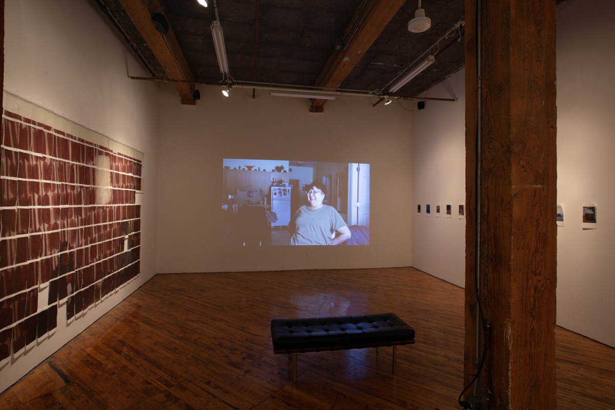 Jake Kimble: Installation view, large mural printed on paper towels, layer out in a grid formation, and video projection on the central wall.