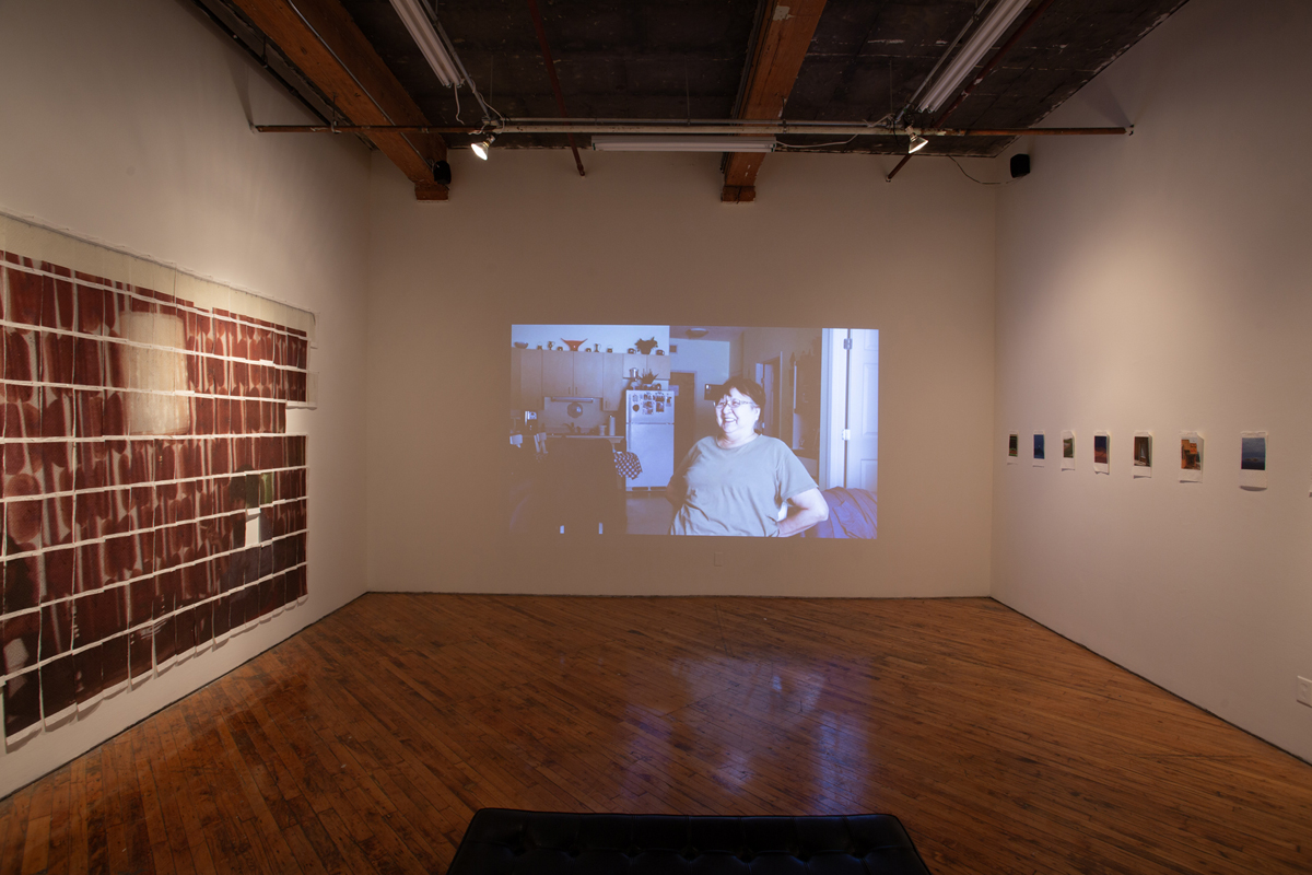 Jake Kimble: Installation view, large mural printed on paper towels, layer out in a grid formation, and video projection on the central wall.