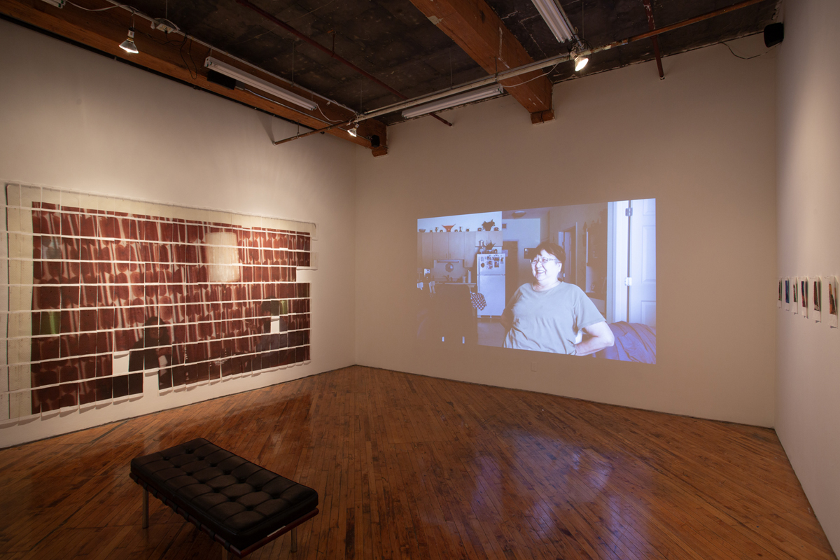 Jake Kimble: Installation view, large mural printed on paper towels, layer out in a grid formation, and video projection on the central wall.