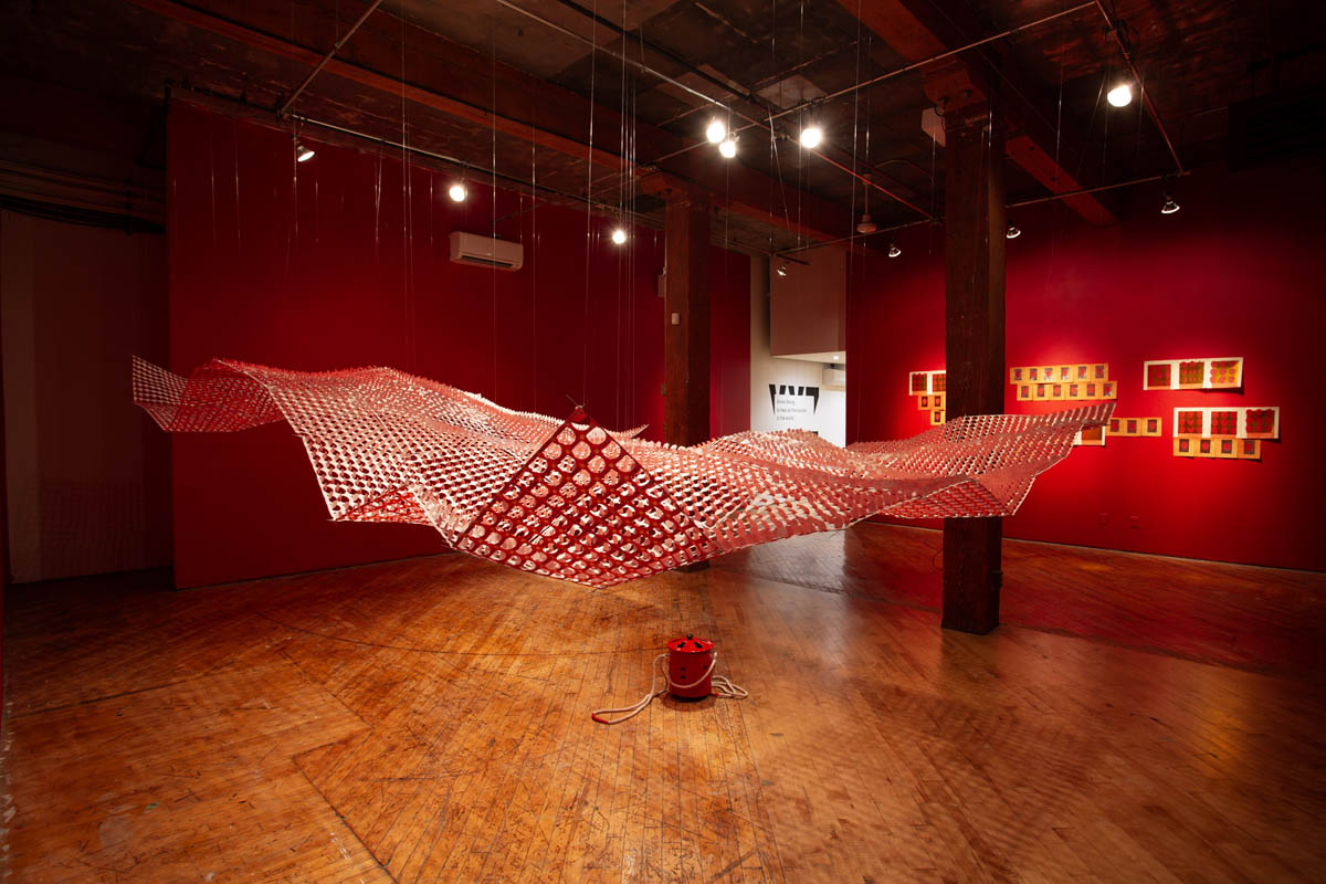 Annie Wong: Installation view of large paper sculpture, hanging from the ceiling, gallery walls are painted red.