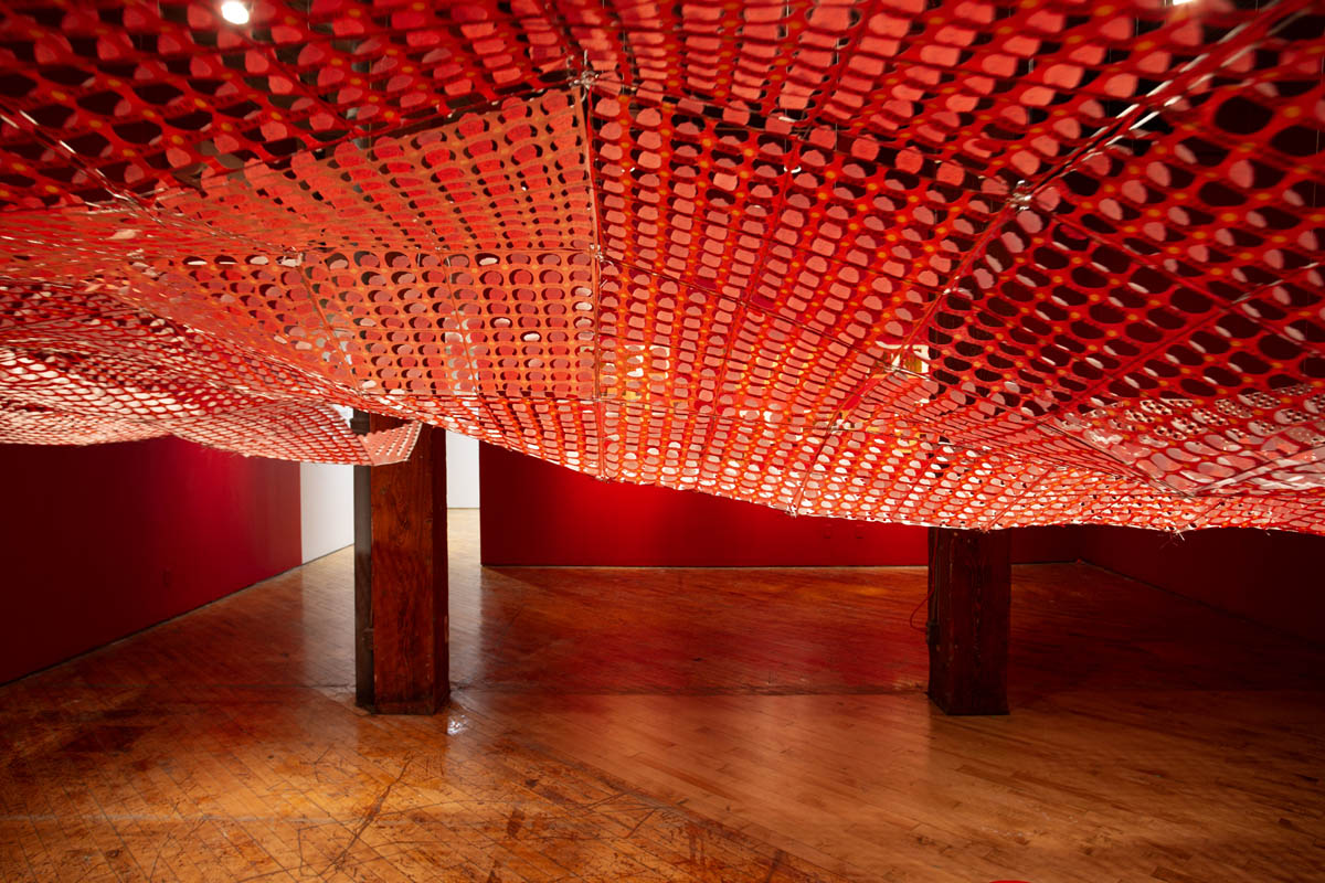 Annie Wong: Installation view of large paper sculpture, hanging from the ceiling, gallery walls are painted red.