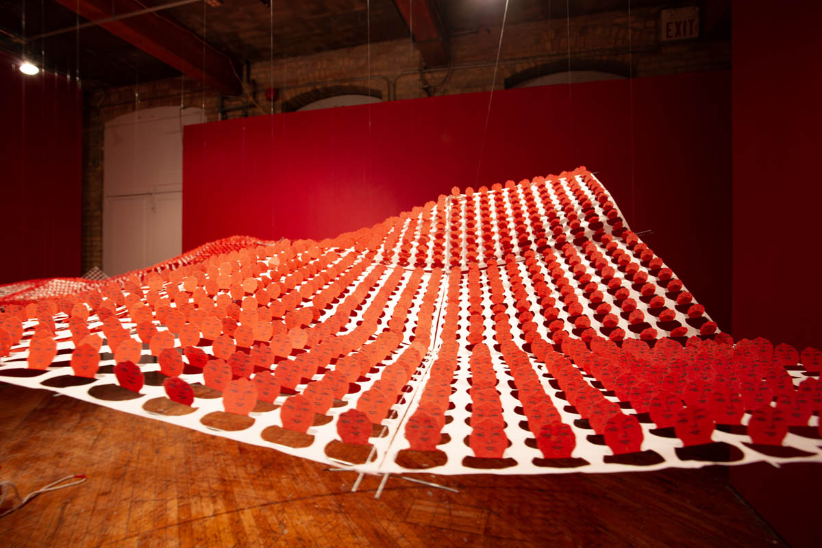 Annie Wong: Installation view of large paper sculpture, hanging from the ceiling, gallery walls are painted red.