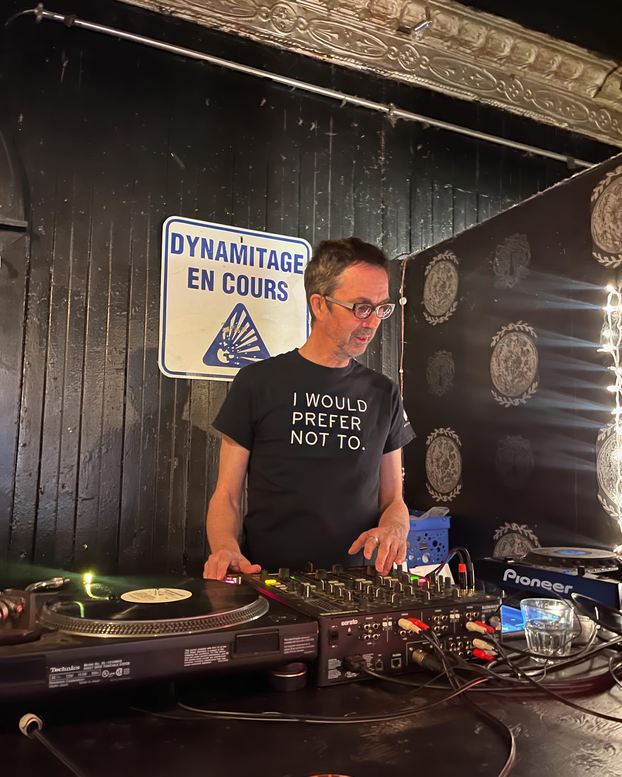 Man with glasses stands inside a DJ booth