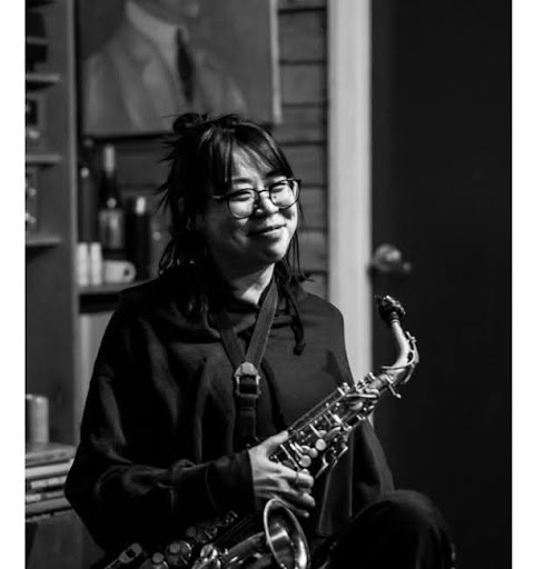 Woman smiles while holding on to her saxophone