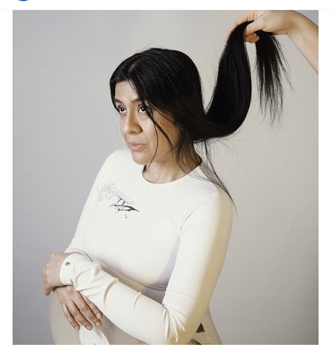 Portrait of a woman with long dark hair being held up by someone's hand