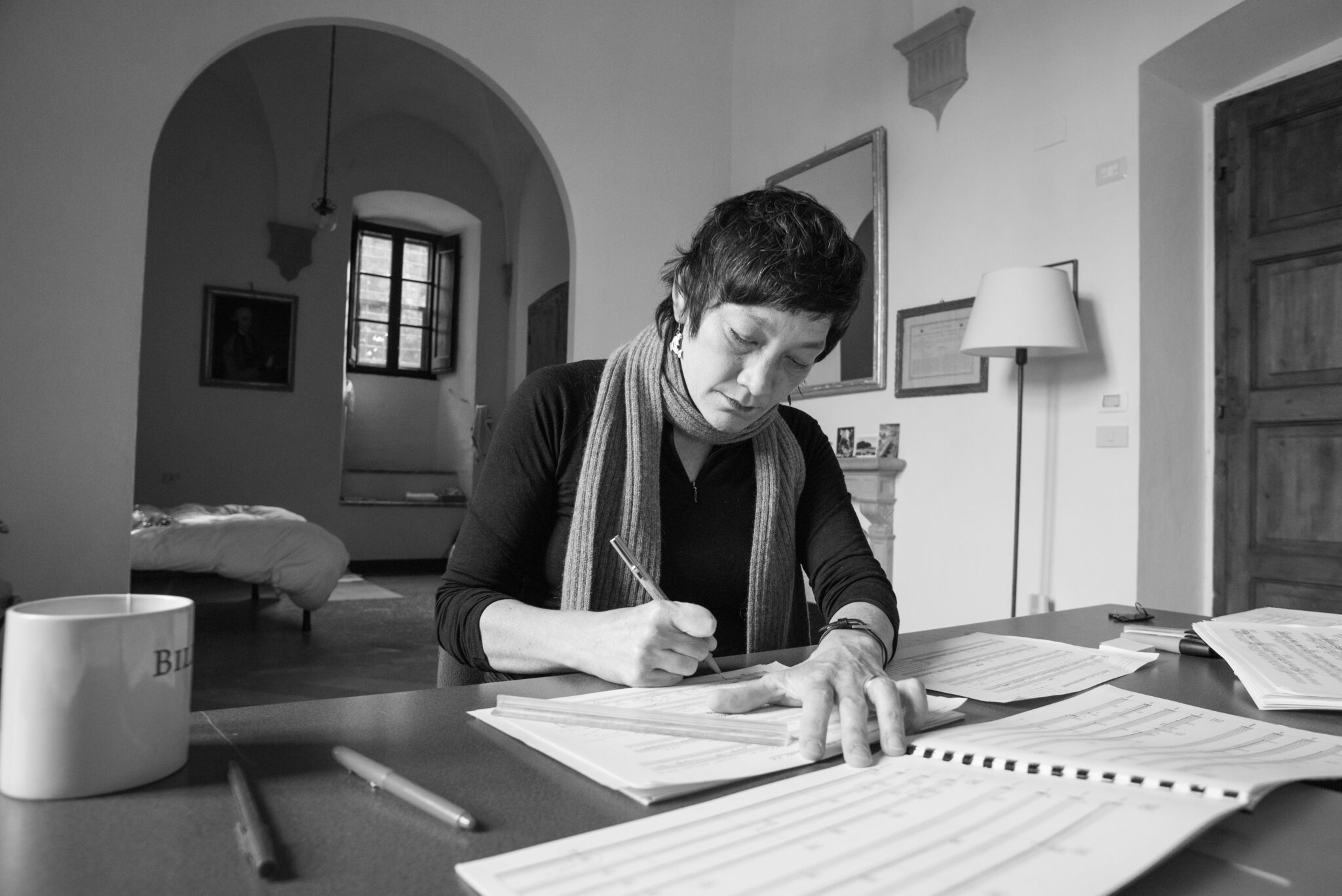 Woman with short hair at a desk with open notebooks in front