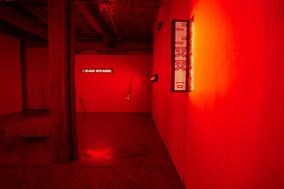 Installation View, red room, dim lights, with LED signs.