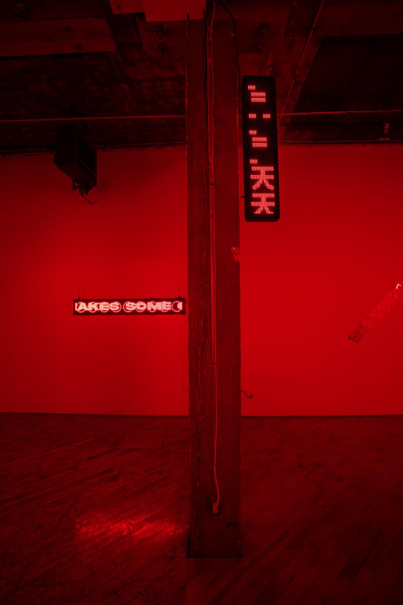 Installation View, red room, dim lights, with LED signs.